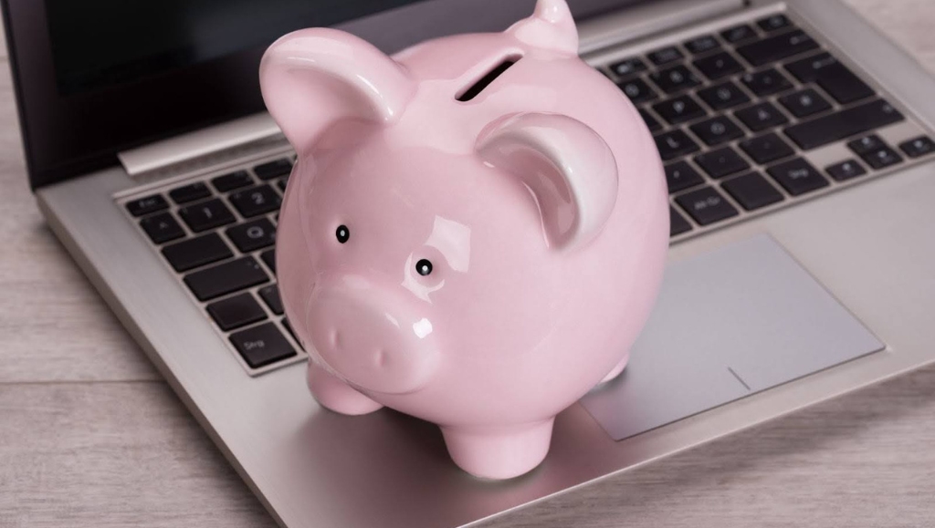 Piggybank on laptop keyboard in money saving concept