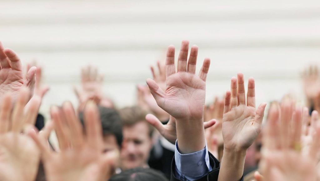 Closeup of crowd raising hands