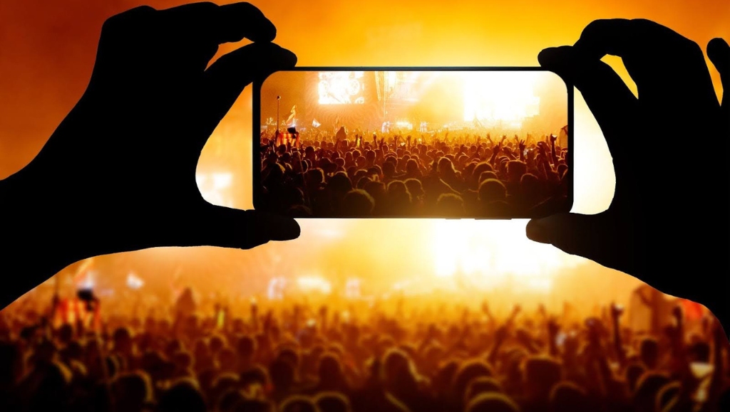 Image of an event attendee capturing an image of the crowd with their cell phone.