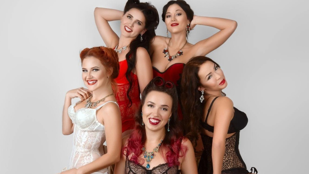 Five young women in corset and lingerie posing near armchair